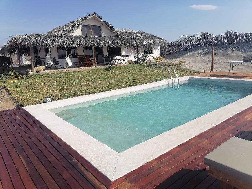 a swimming pool in front of a house at Posada del Mar Vichayito in Los Órganos