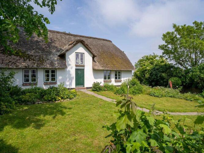 ヴェスターヘーヴァーにあるThe stylishly restored and thatched holiday home is located on a terpの草の庭付き屋根の白い家