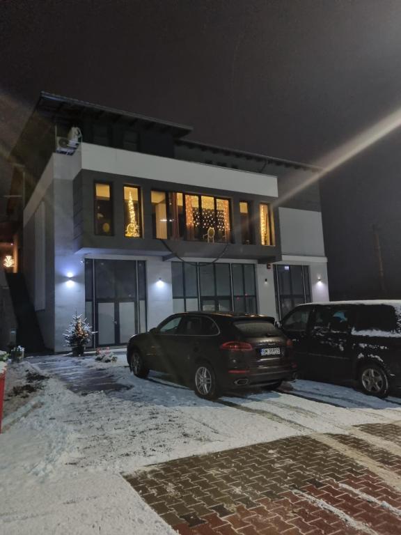 deux voitures garées devant un bâtiment la nuit dans l'établissement NORD APARTAMENTS, à Zalău