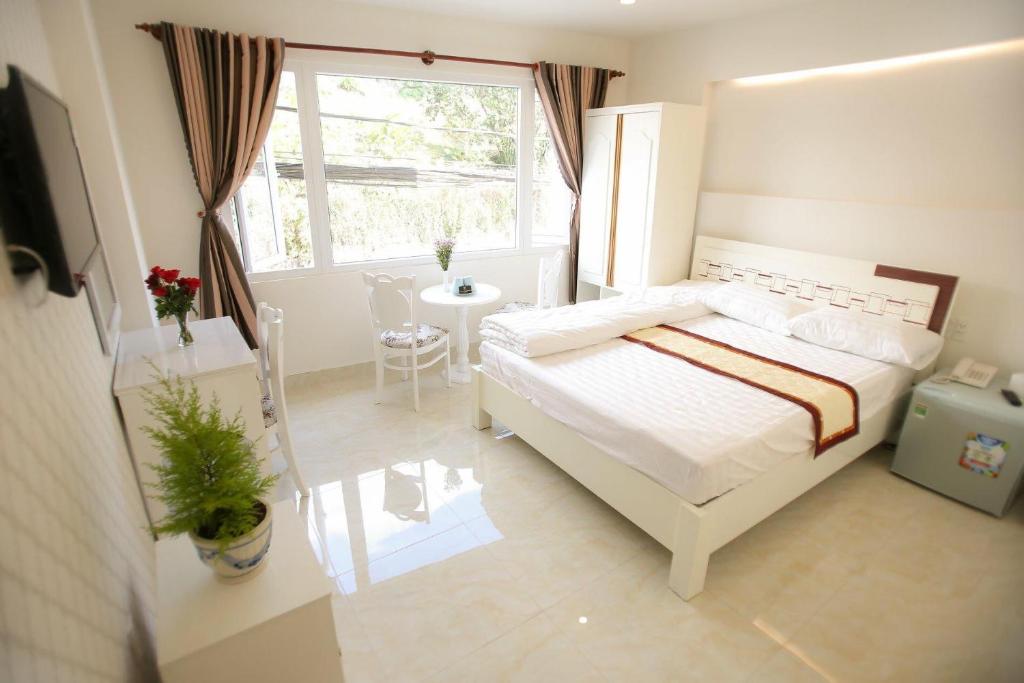 a bedroom with a white bed and a window at Thanh Thanh Hotel in Da Lat