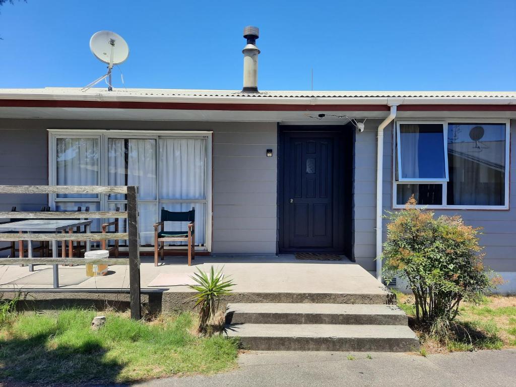 ein Haus mit einer blauen Tür und einem Stuhl auf einer Veranda in der Unterkunft Mount Budget Accommodation in Tauranga