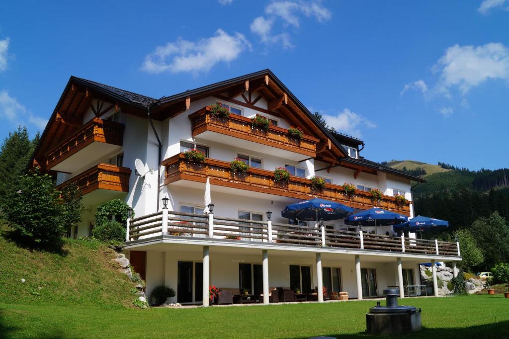 un grand bâtiment avec des parasols en face de celui-ci dans l'établissement Alpenhof Reuterwanne, à Wertach