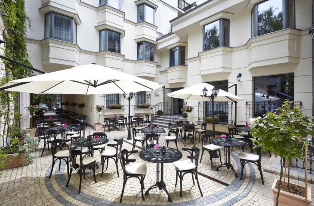 a group of tables and chairs with umbrellas in front of a building at Hotel Logos Kraków in Krakow