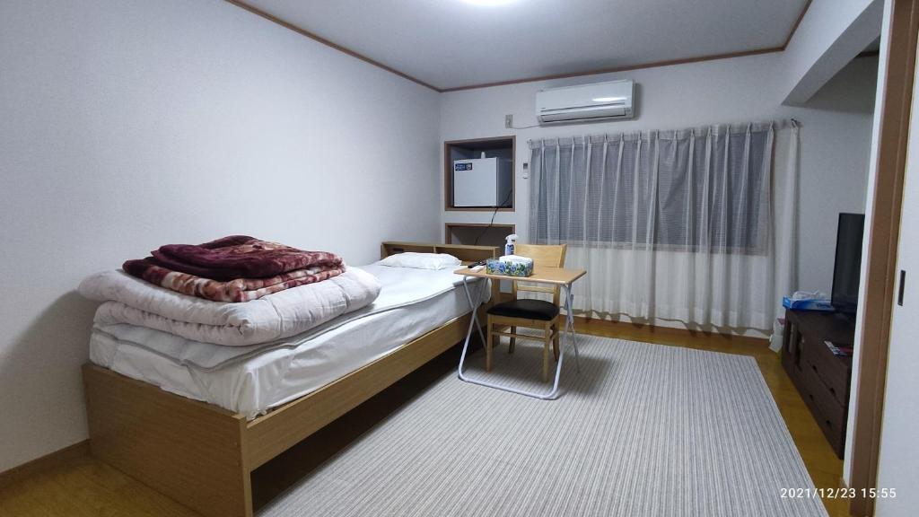 a bedroom with a bed with a desk and a television at あけぼの館 in Iizuka