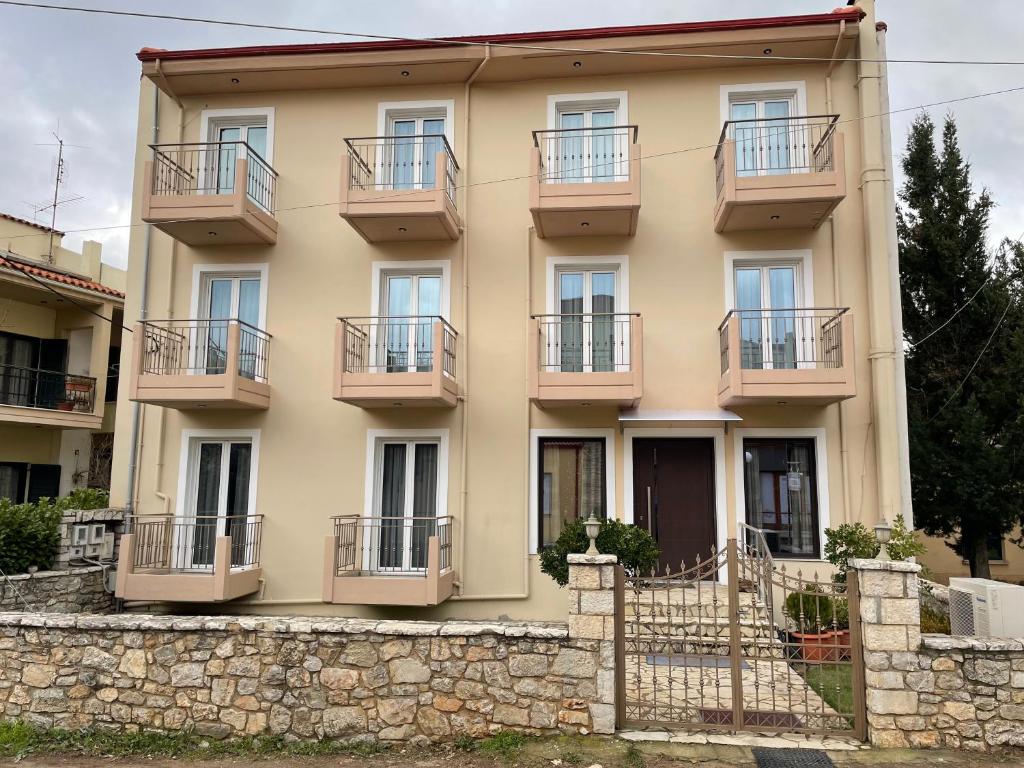 an apartment building with balconies and a stone wall at Varvitsiotis Studios in Kalavrita