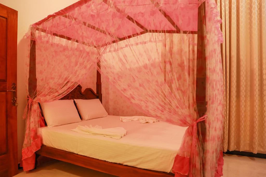 蒂瑟默哈拉默的住宿－JAMI River Side Hotel & Yala Safari Place，卧室配有带粉红色窗帘的天蓬床