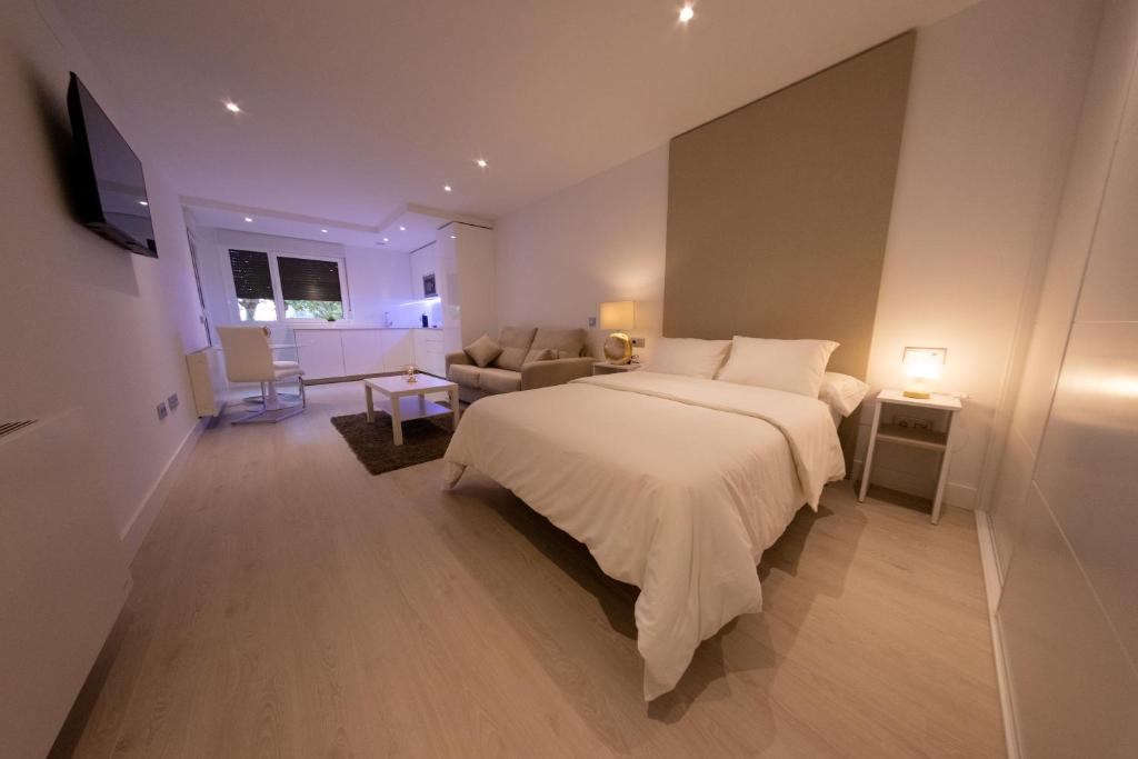 a bedroom with a large white bed and a couch at Apartamentos Palacio de Yolanda in Zamora