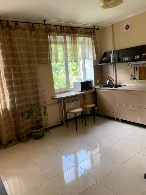 eine Küche mit einem Waschbecken, einem Tisch und einem Fenster in der Unterkunft Апартаменты на пр Гагарина in Dnipro