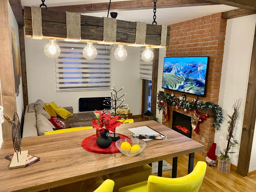 uma sala de estar com uma mesa de madeira e cadeiras amarelas em Zlatiborske Noći em Zlatibor