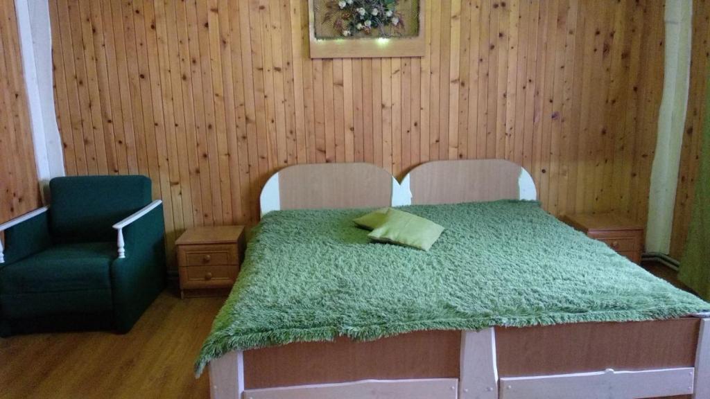 a bedroom with a bed with a green comforter and a chair at Kray Dorogy in Yaremche