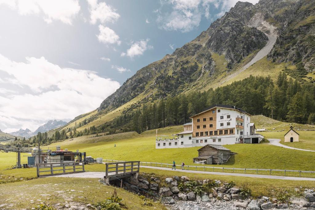 a building in a field with a mountain in the background at Berghotel Bodenalpe in Ischgl