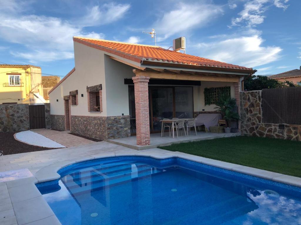 a villa with a swimming pool in front of a house at Acogedora casa rural con piscina particularBarlow in Abadía