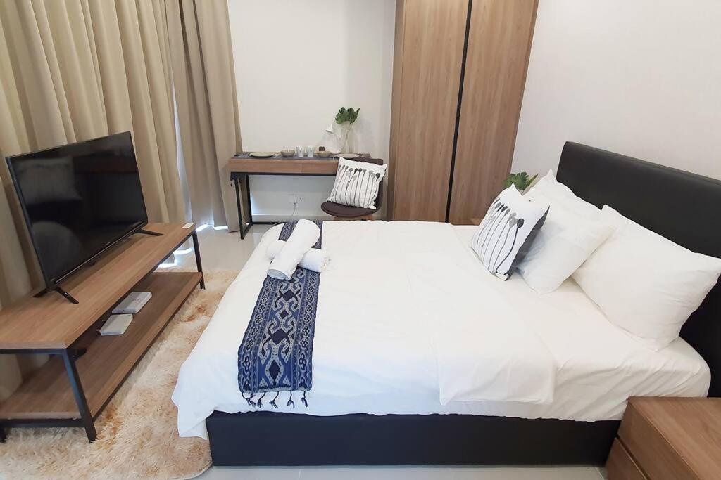 a bedroom with a large bed and a television at KOZI Square New SGH Cozy Home LV7B in Kuching