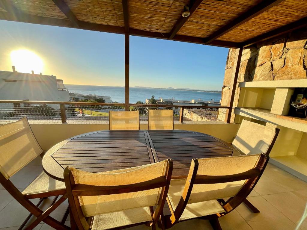 Quartier Punta Ballena 2 dorm en suite في بونتا دل إستي: طاولة وكراسي على شرفة مطلة على المحيط