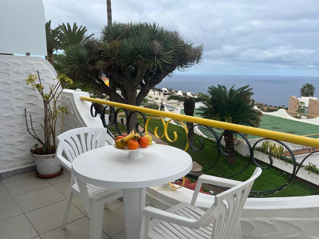 - une table et des chaises blanches avec un bol de fruits sur le balcon dans l'établissement Studio sea front view & pool, à Tacoronte