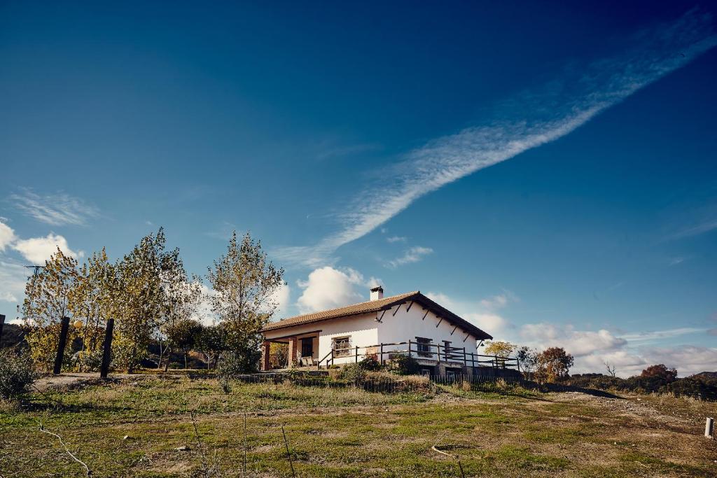 Fuente del Arco的住宿－Casa Rural Sierra Jayona，一座带围栏的田野上的白色小房子