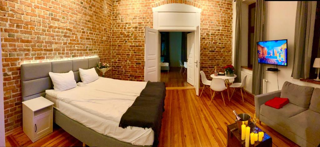a bedroom with a bed and a brick wall at Apartament 511 Katarzyny in Toruń