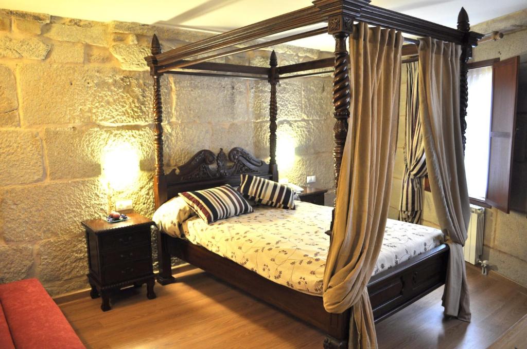 a bedroom with a canopy bed in a stone wall at Hotel Boa Vila in Pontevedra