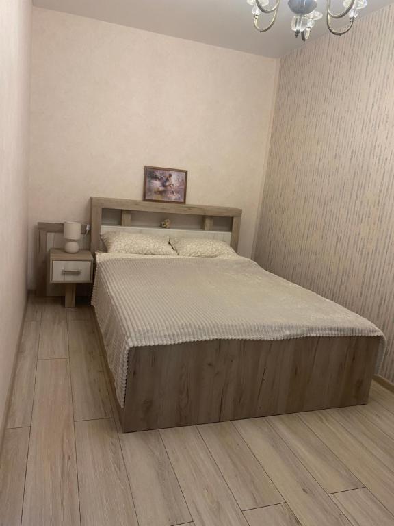 a bedroom with a large bed and a chandelier at Уютные апартаменты на Трехсвятской in Tver