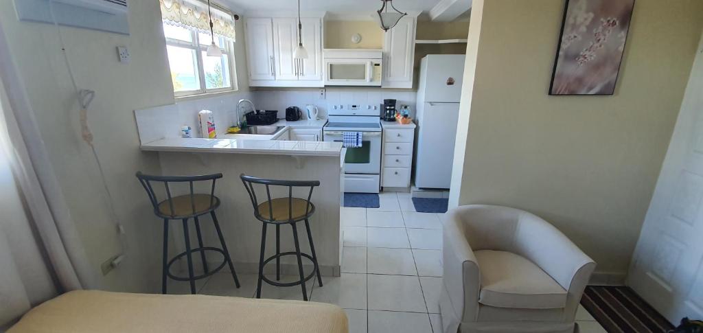 a kitchen with two bar stools and a counter top at Hastings Towers 4D - Studio Apt Opp Beach in Bridgetown