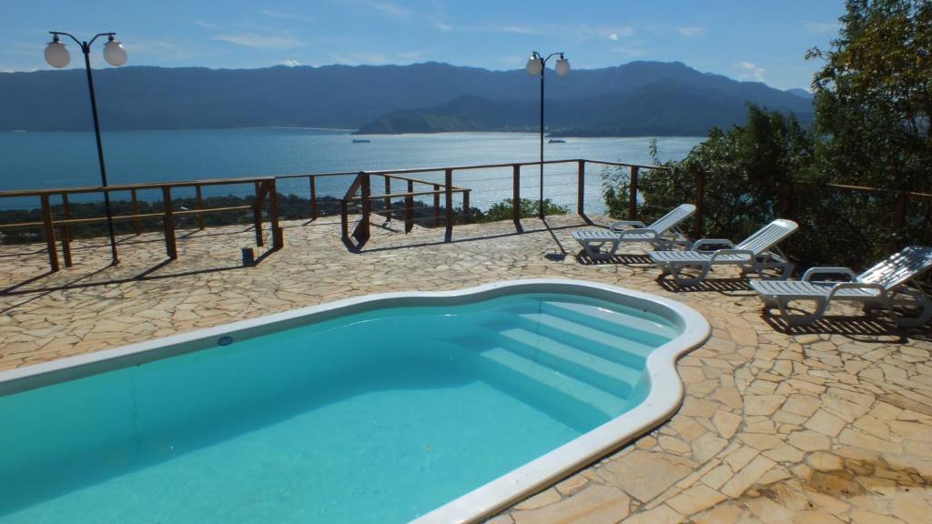 una piscina con sillas y vistas al agua en Chalés Mirante Altos Ares, en Ilhabela