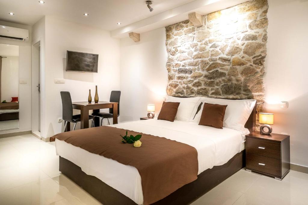 een slaapkamer met een groot bed en een stenen muur bij Split Oasis Studio Apartments in Split