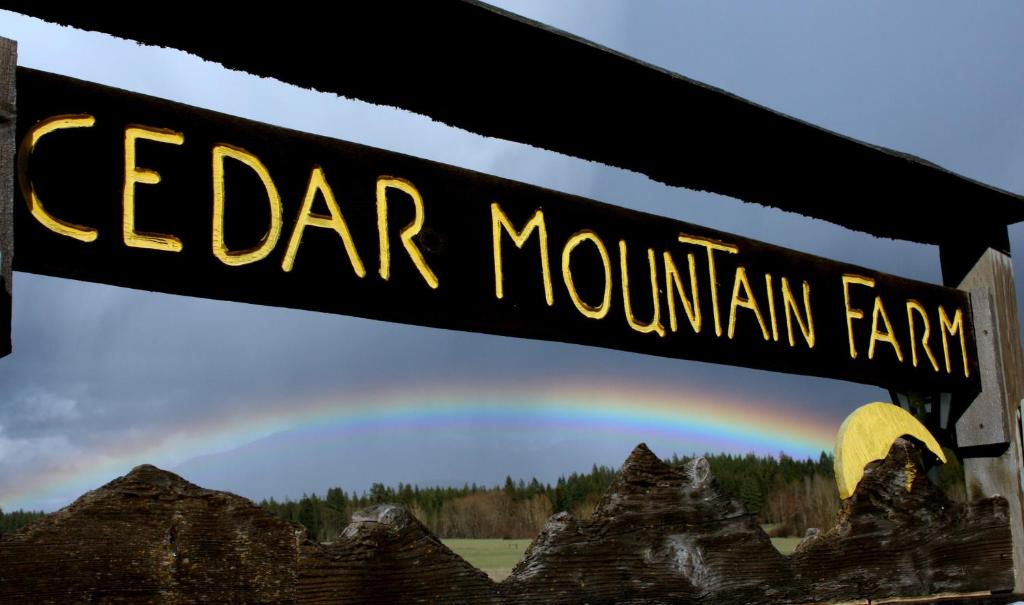 a sign that reads cedar mountain farm with a rainbow in the background at Cedar Mountain Farm Bed and Breakfast LLC in Athol