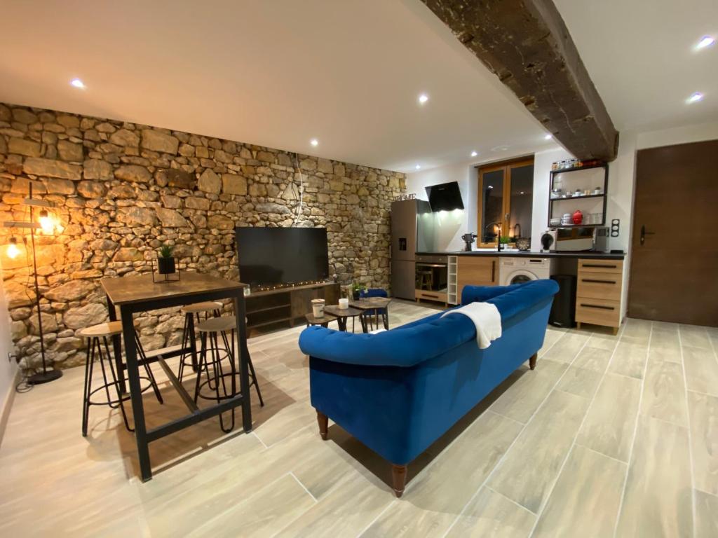 a living room with a blue couch and a stone wall at Dormelles : magnifique maison de ville in Dormelles
