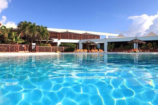 a large pool of blue water in front of a building at Studio Douceur des iles in Belle-Allée