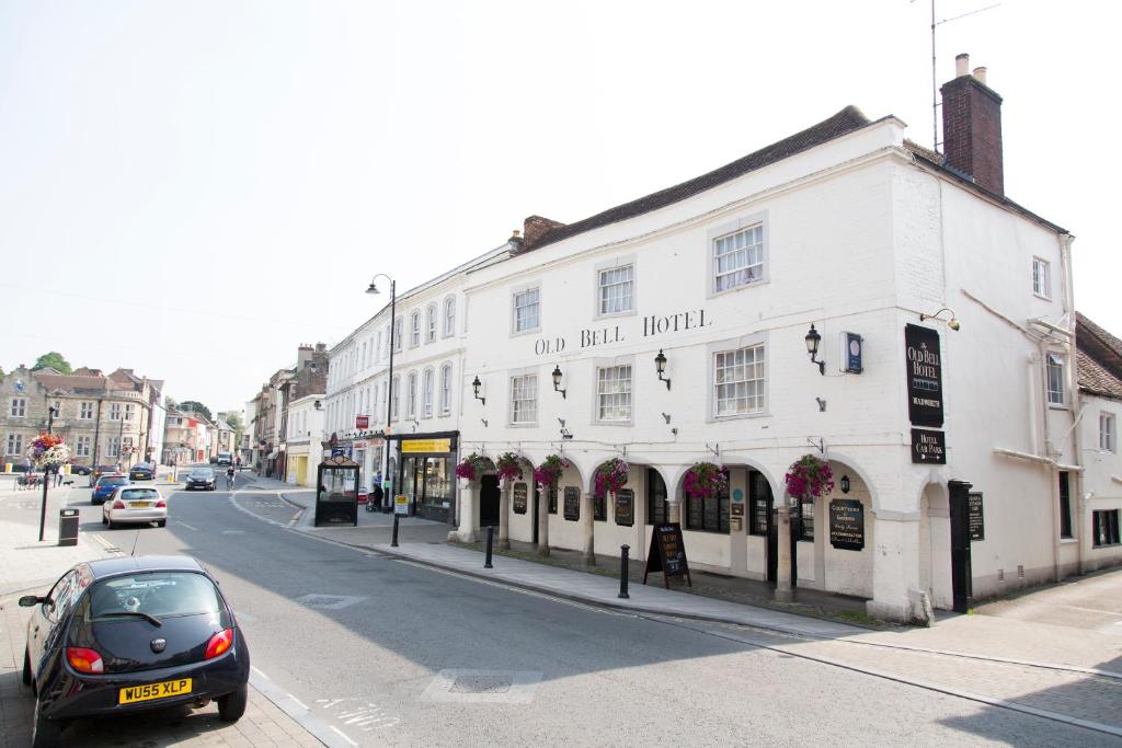 a car parked in front of a white building on a street at The Old Bell - Warminster in Warminster