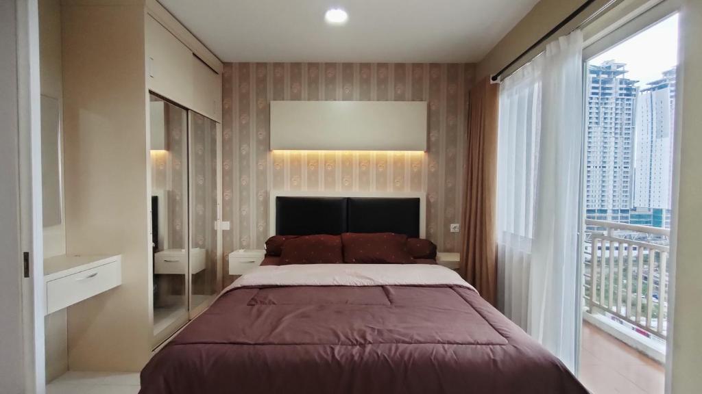 Kozy Room Sentul Tower Apartemen في بوغور: غرفة نوم بسرير كبير ونافذة كبيرة