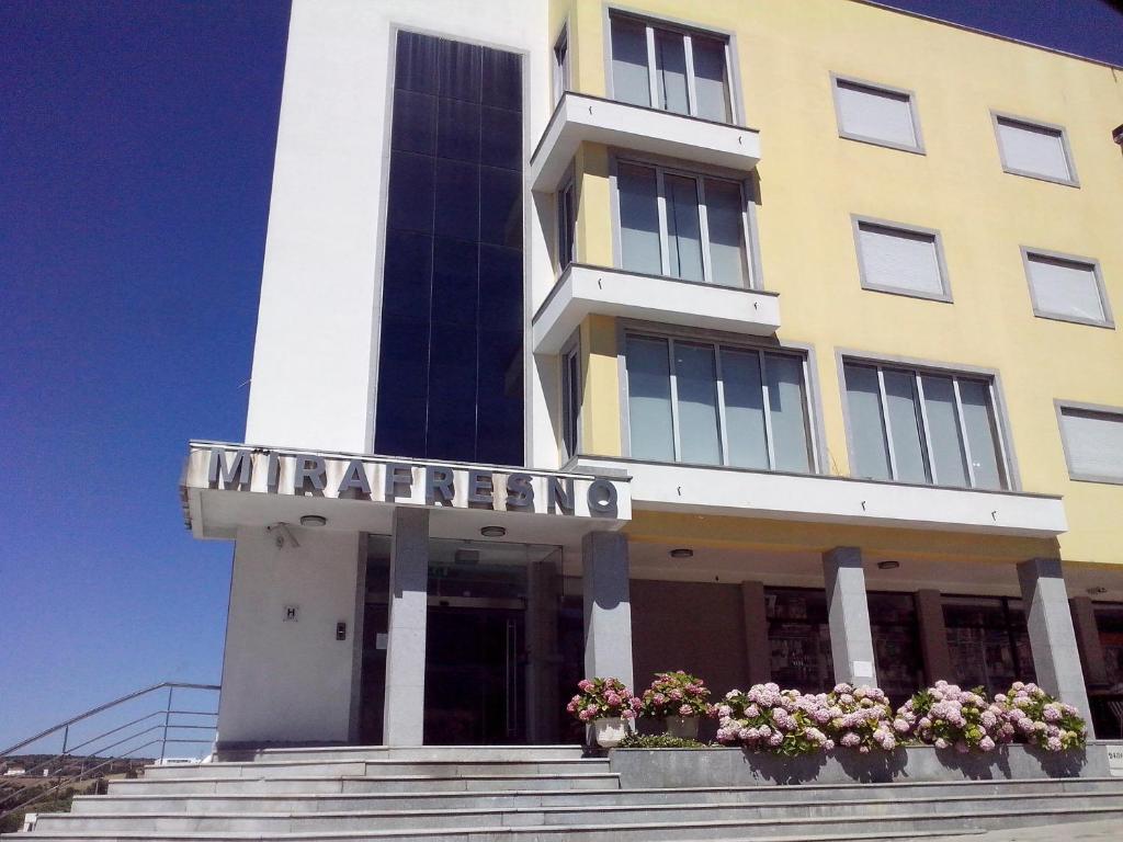 a yellow building with potted plants in front of it at Hotel Mirafresno in Miranda do Douro