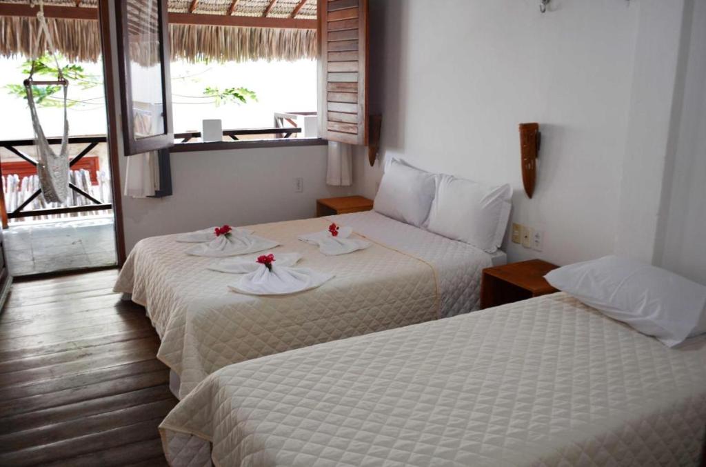 um quarto de hotel com duas camas com flores em Vila Moana Jeri em Jericoacoara