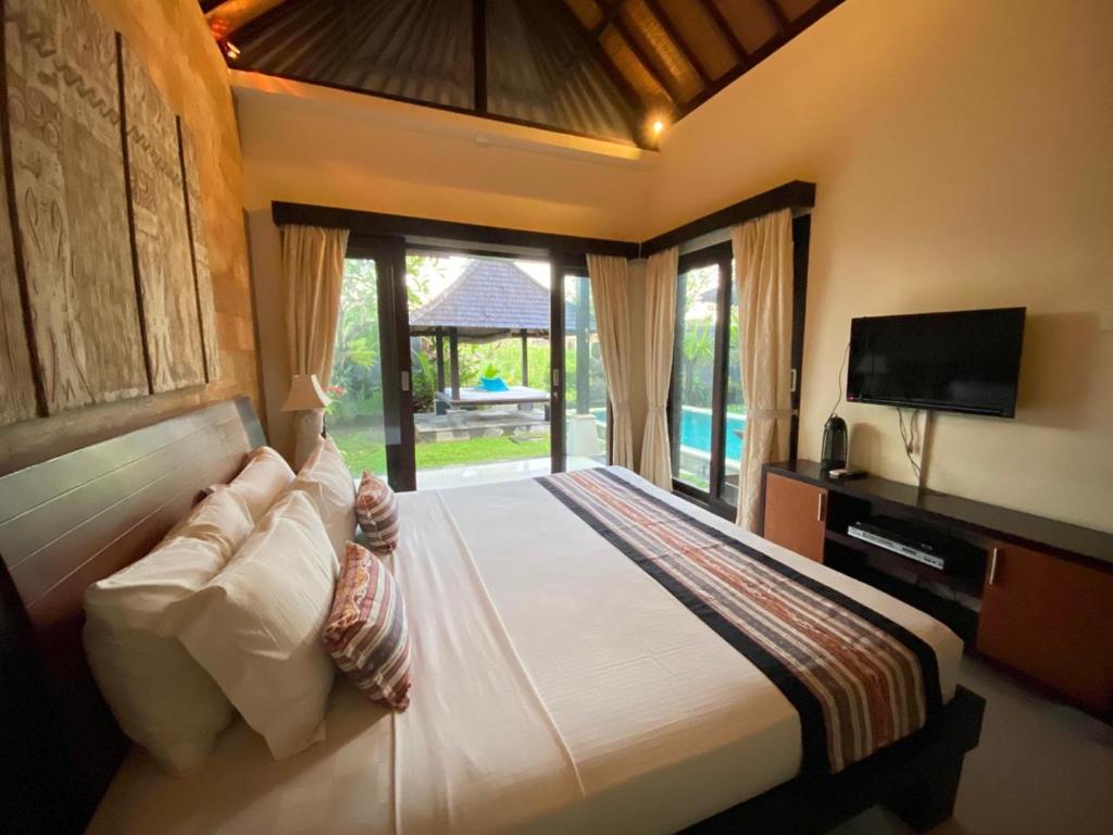 a bedroom with a large bed and a television at Villa Buddha Umalas in Kerobokan