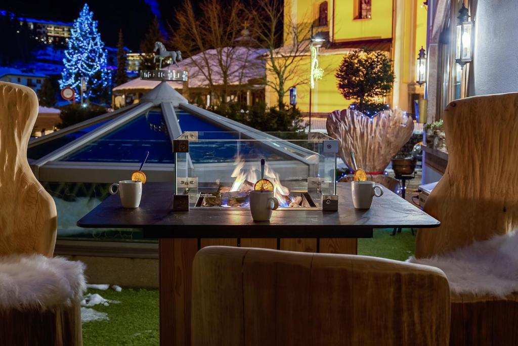 a table with a fireplace in front of a window at Cavallino Lovely Hotel in Andalo