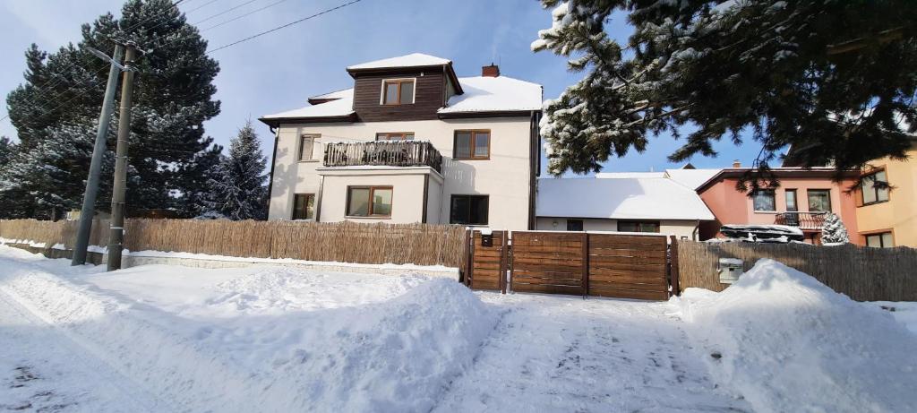 a house with a fence and a pile of snow at Privát Tatry Štrba in Štrba