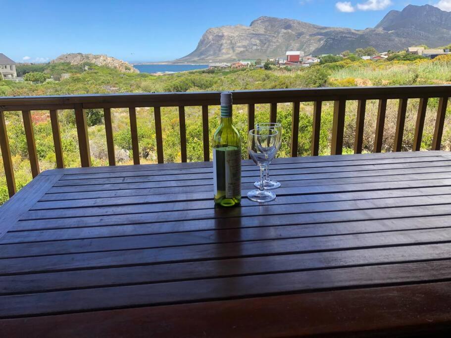 a bottle of wine and a wine glass on a wooden table at Adorable 2 bedroom seaside vacation home in Kleinmond