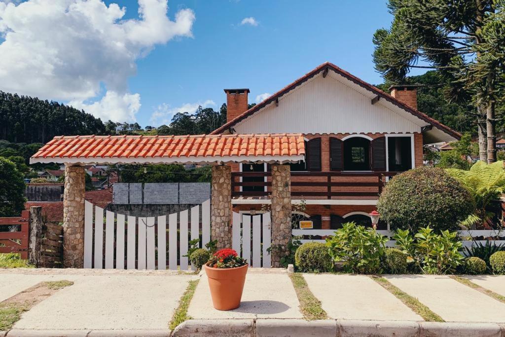 una casa con una valla blanca y una maceta de flores en Chalés Del Rincon en Monte Verde