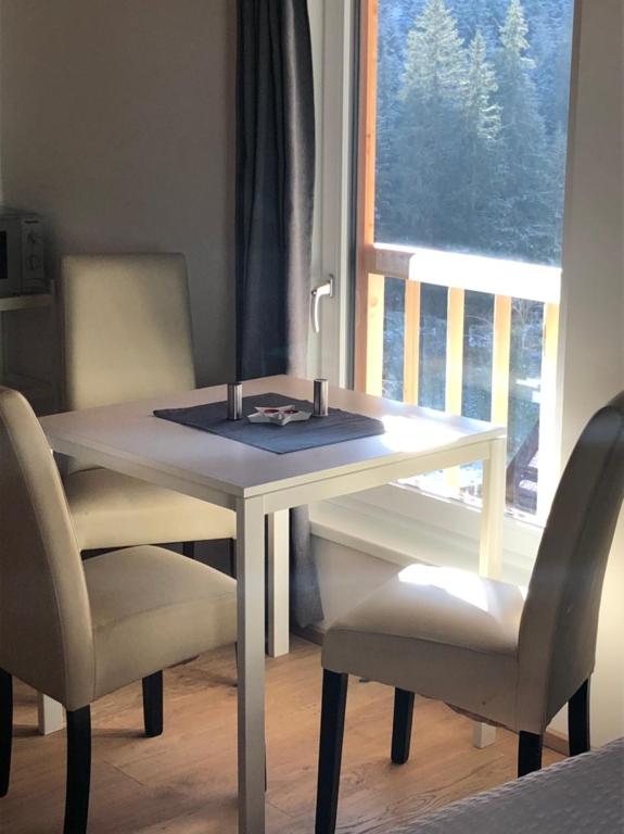 einen weißen Tisch mit zwei Stühlen und einem Fenster in der Unterkunft EMMA's Studio in Gerlos