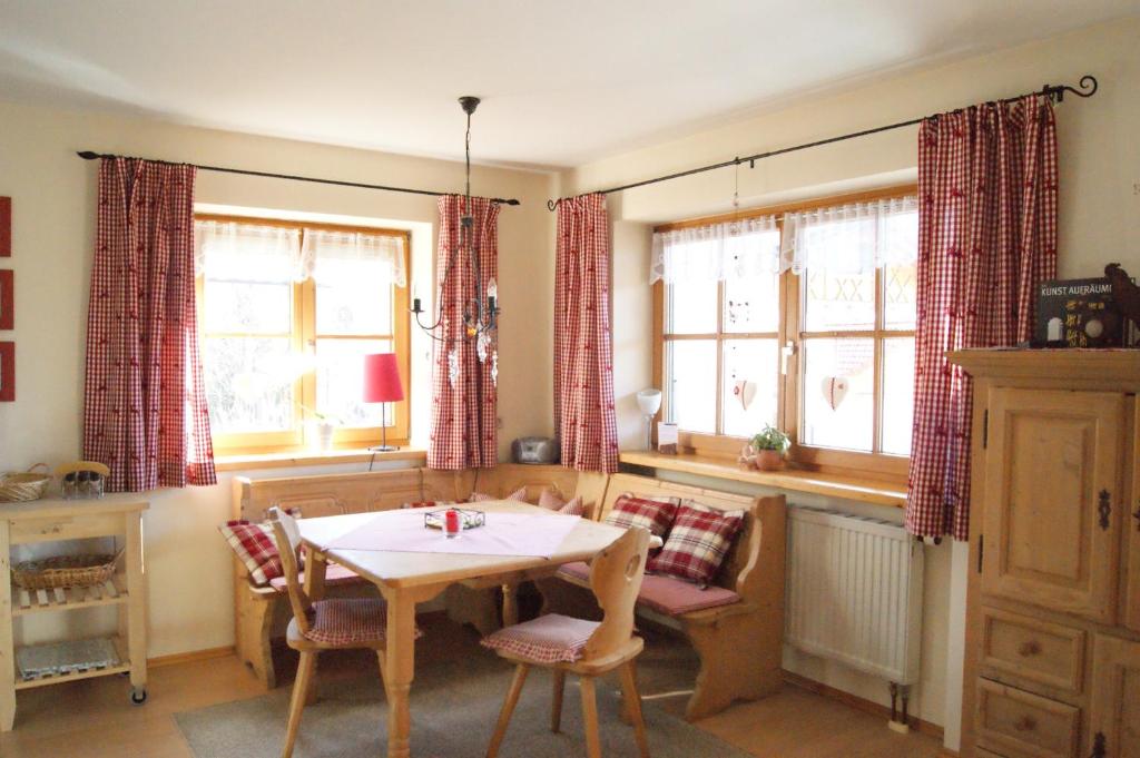a dining room with a table and chairs and windows at Allgäu-Moni Trauchgau in Halblech