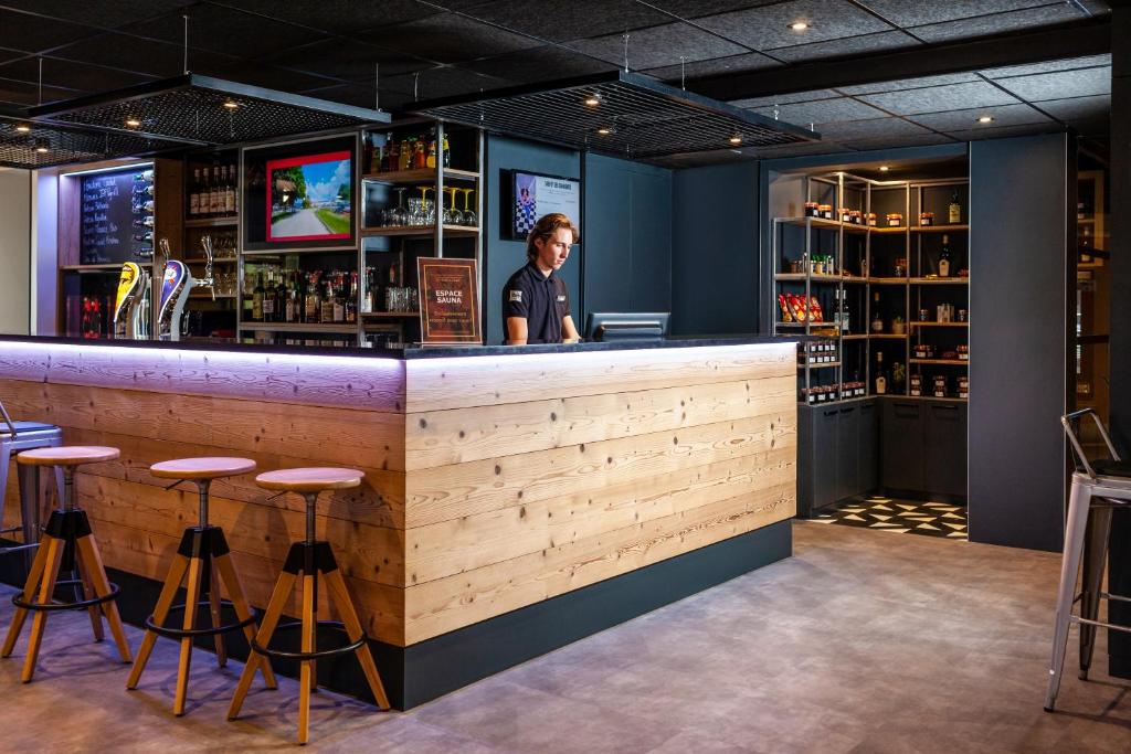 a man standing at a bar in a restaurant at ibis Pontarlier in Pontarlier