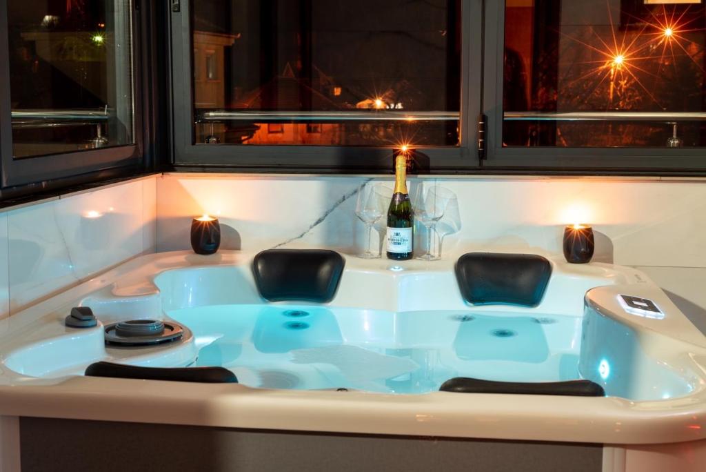 a bath tub with two chairs and a bottle of wine at IN LUX SPA APARTMAN in Vrnjačka Banja