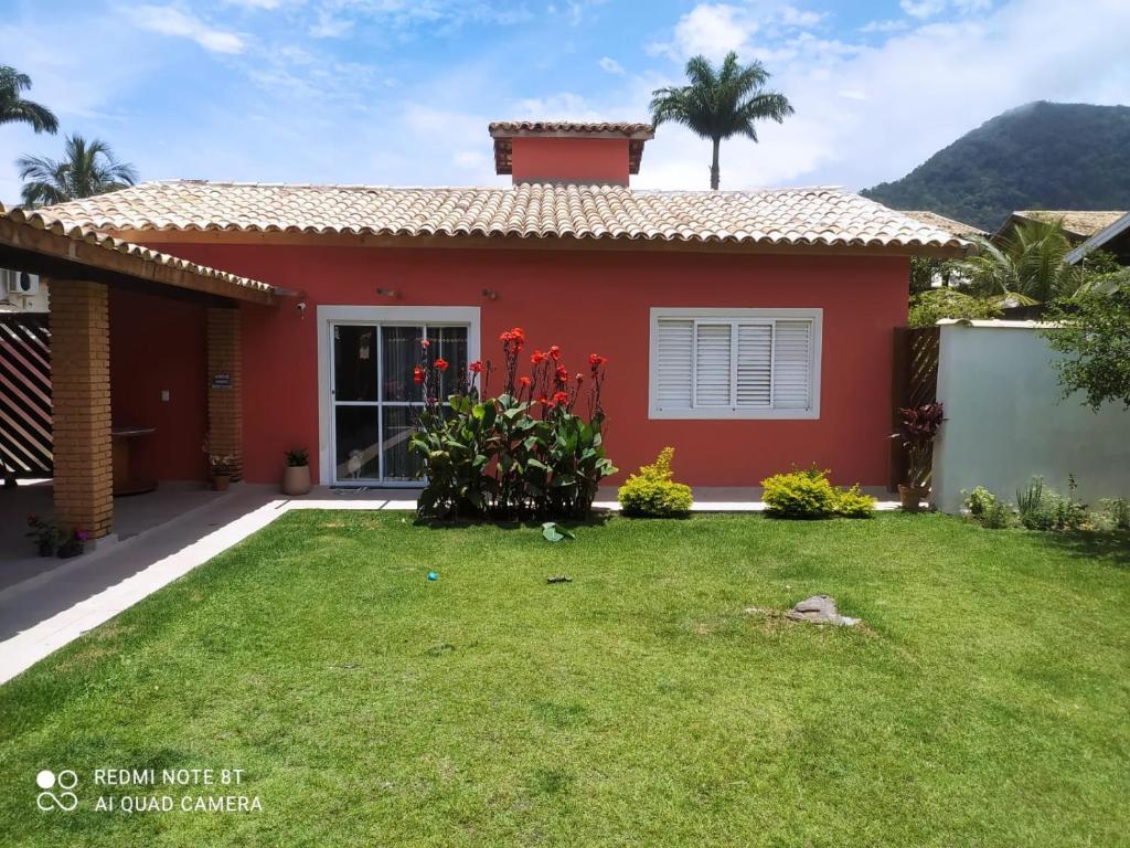 a red house with a lawn in front of it at Cantinho de Barê in Barequeçaba