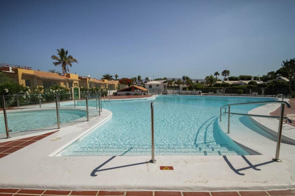 a large swimming pool with blue water in a resort at cozy & modern bungalow w/private garden bbq+wifi in Maspalomas