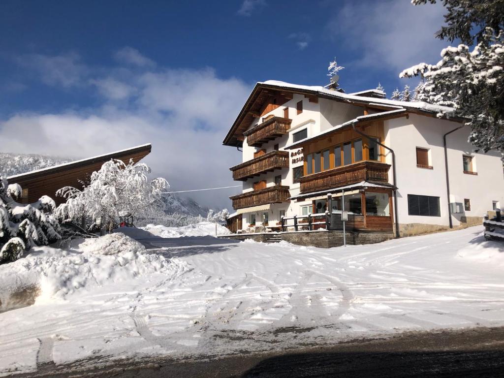 un edificio cubierto de nieve delante en Garni Irsara, en San Cassiano