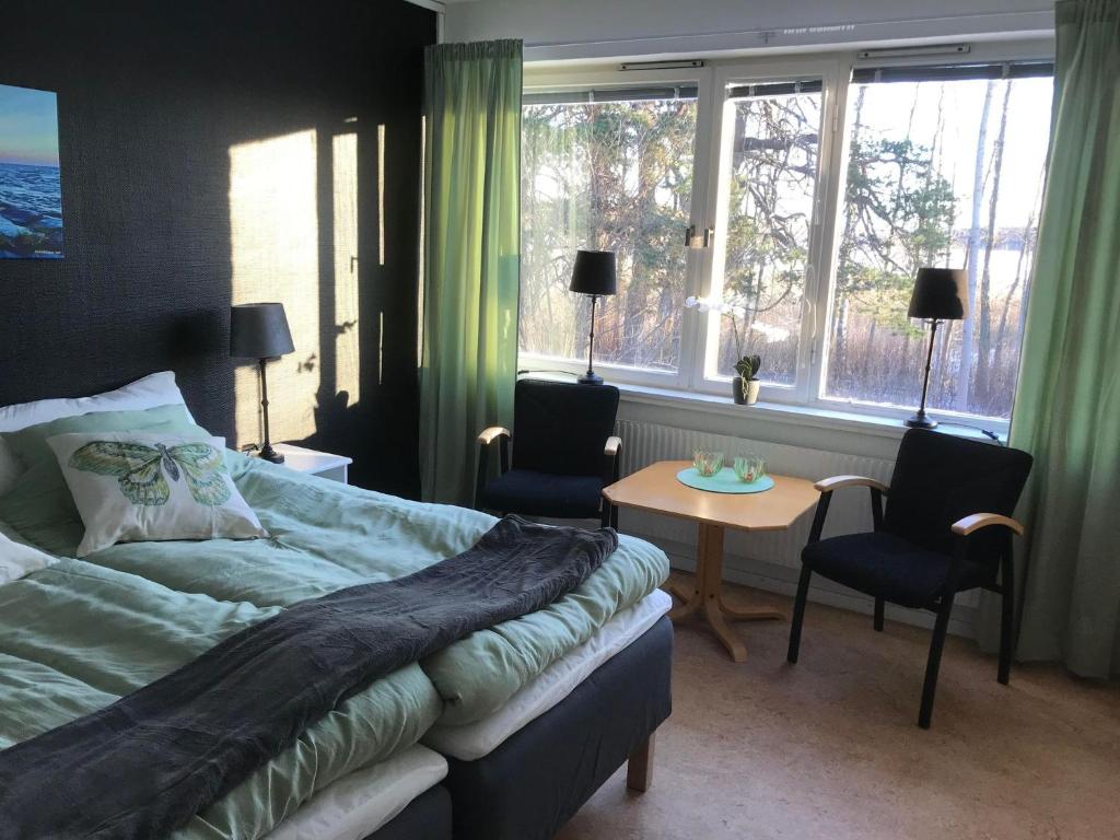 1 dormitorio con cama, mesa y ventanas en Hammarö Vandrarhem, en Hammarö