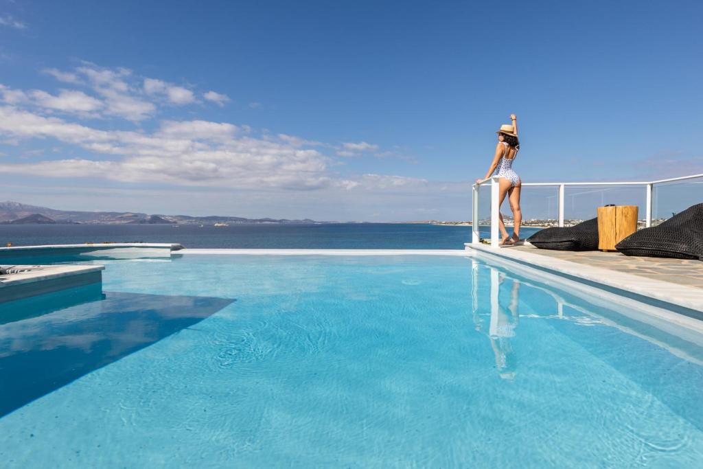 a woman sitting on the edge of a swimming pool at Villa Paradise in Naxos in Plaka