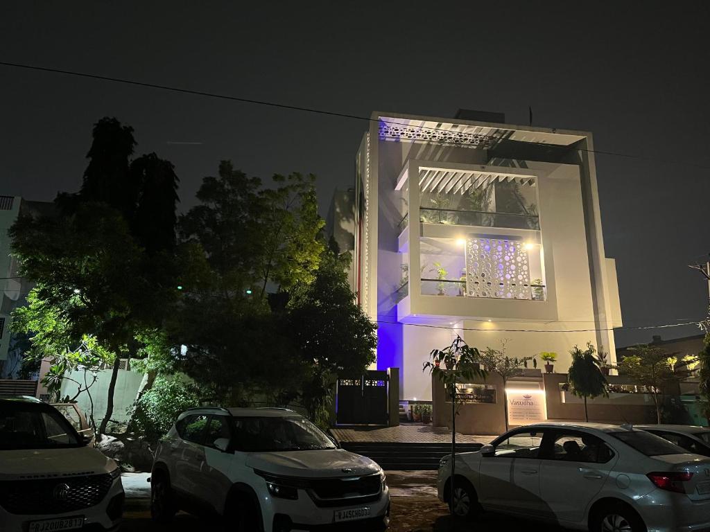 un edificio con coches aparcados delante de él por la noche en Hotel Vasudha Palace, en Jaipur