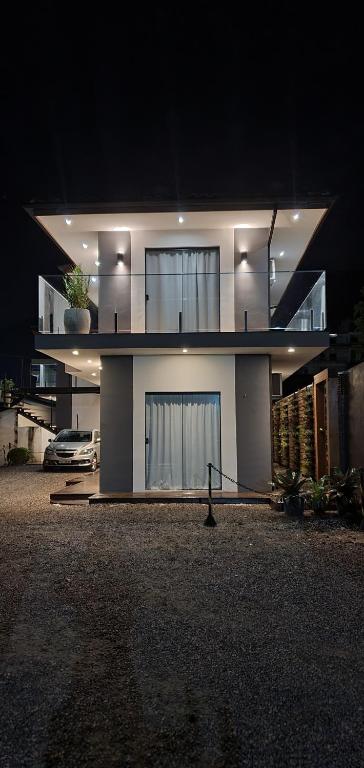 a large white house at night with a car at Rei dos Mares Suítes in Ubatuba