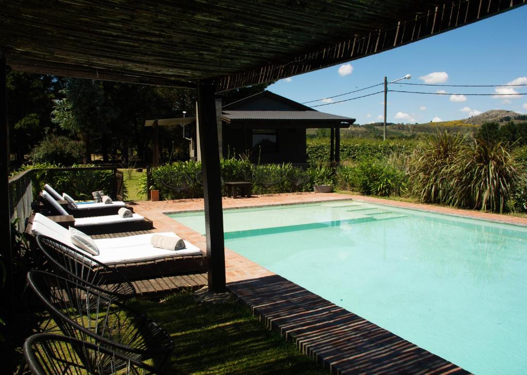a swimming pool with lounge chairs next to it at Refugio En Las Sierras in Tandil